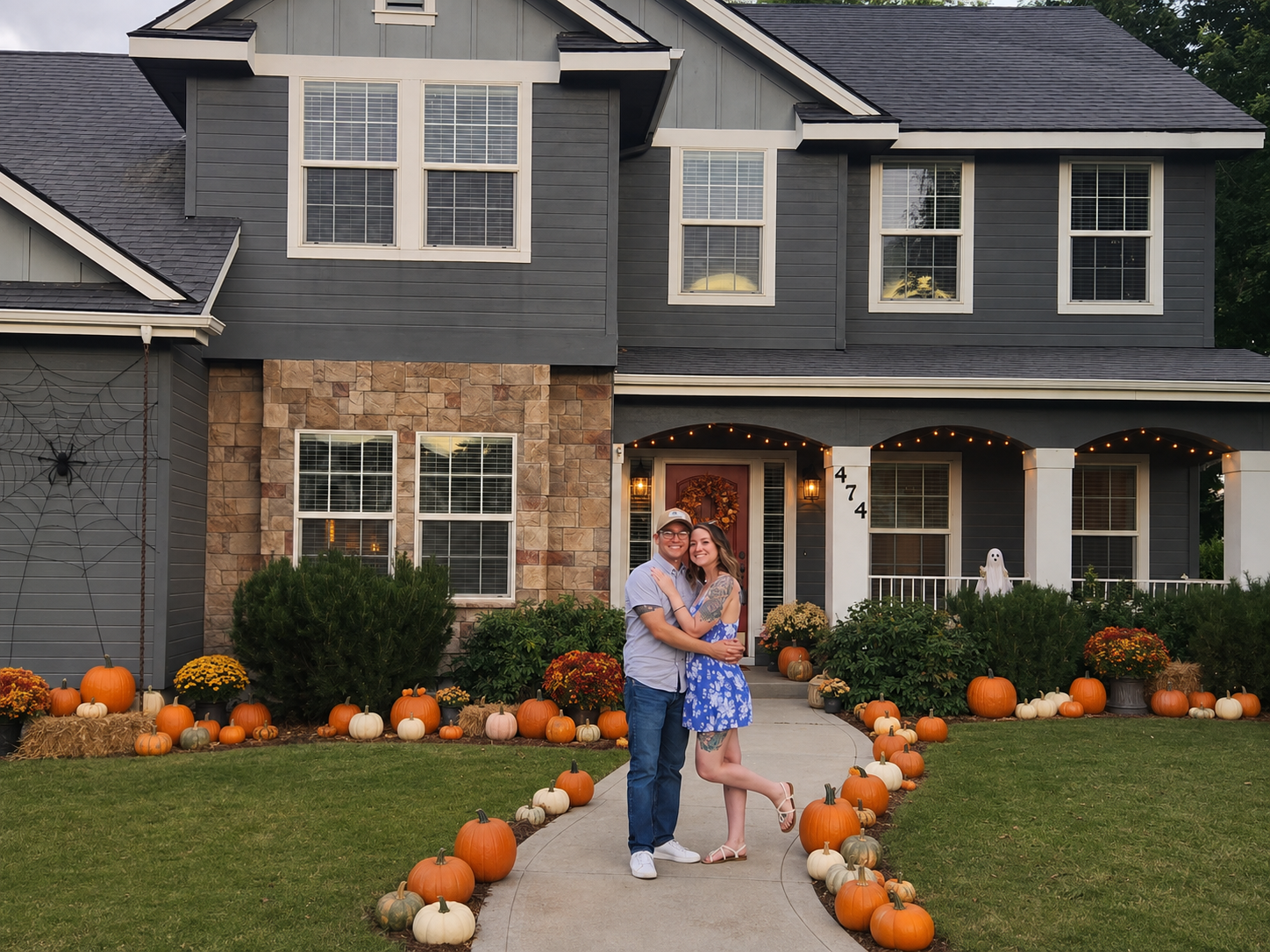 Carrie and Travis Howse standing together on the pumpkin-lined walkway of a Treasure Valley home